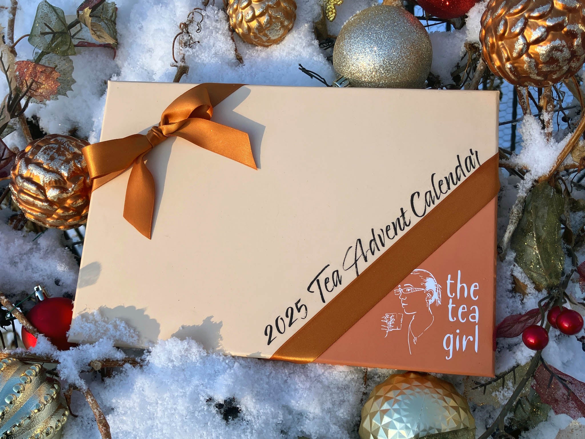 Tea Advent Calendar with decorative ornaments on a snowy background